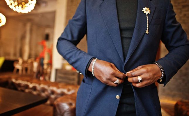 Close up hands of fashionable african american man in suit tied button.