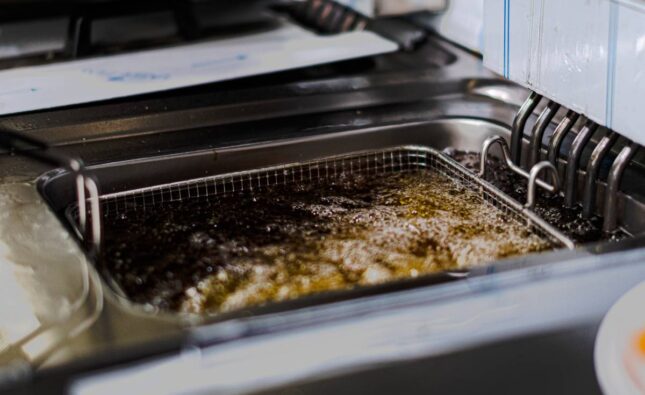 A high angle shot of french fries being fried in a lot of oil in the kitchen